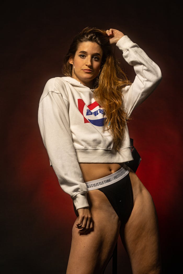 Portrait of a woman in a hoodie with dramatic lighting and bold pose.