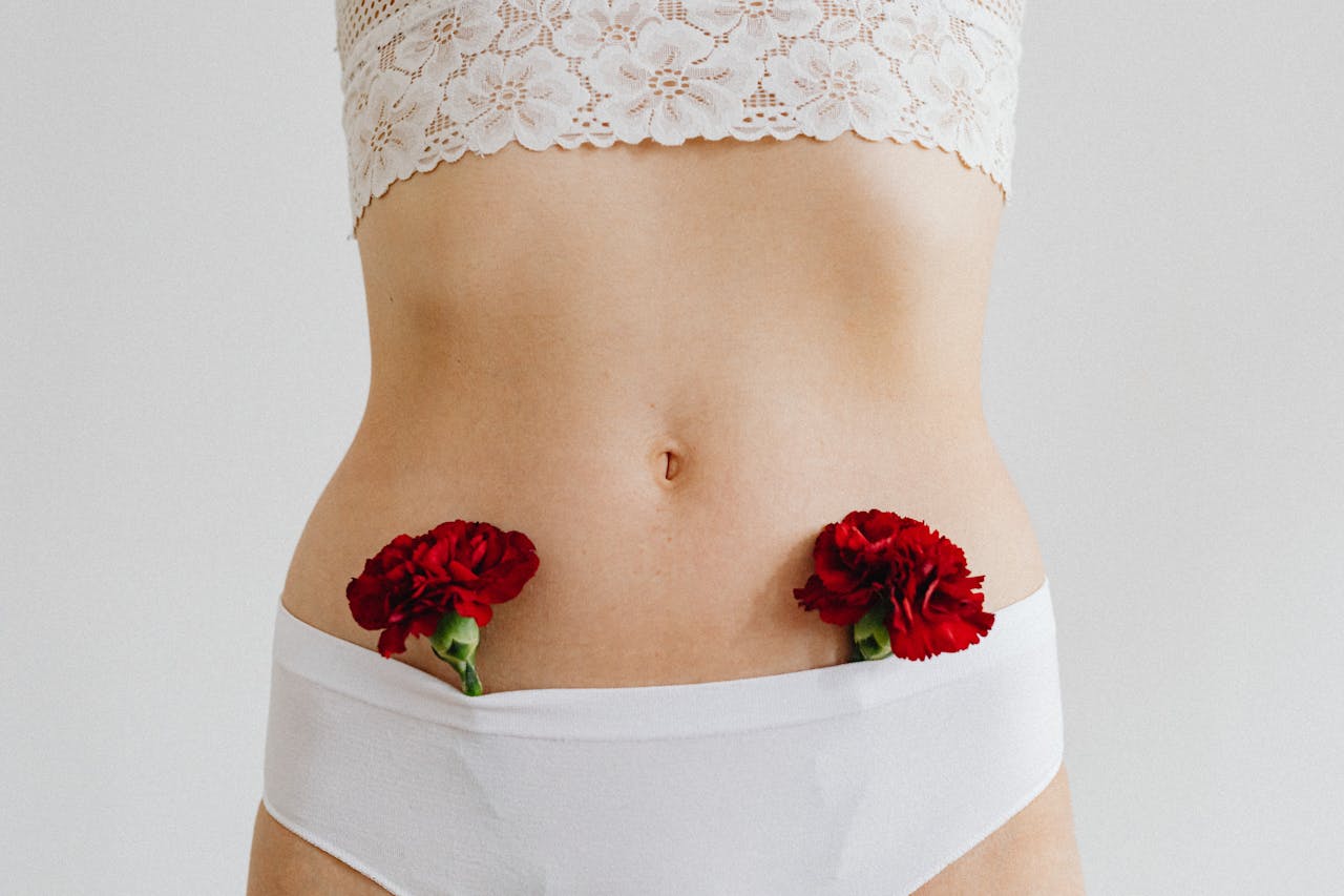 About Close-up of a woman wearing white lingerie with red carnations. Delicate and artistic composition.
